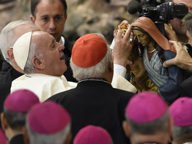 Pope Francis (L) adjusts crowns on a statue of the Virgin Mary during an audience to the p