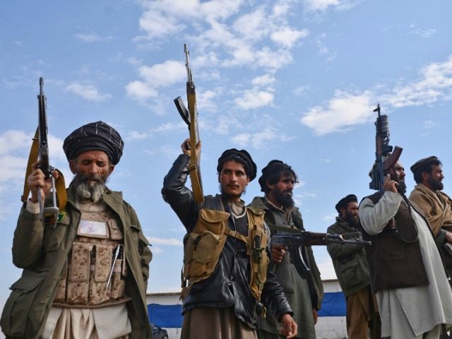 Afghan militia men raise their weapons as they stand guard in the Achin district of Nangar