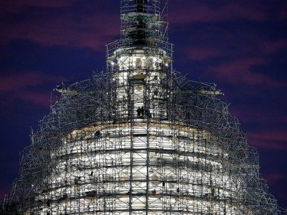 Workers stand on the scaffolding that surrounds the dome of the US Capitol which is underg
