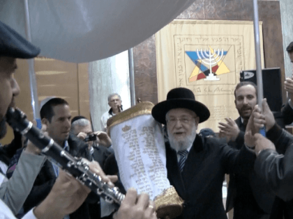 Rabbi Yisrael Meir Lau holding the new Torah scroll on which the names of the 72 soldiers killed in Operation Protective Edge are embroidered.