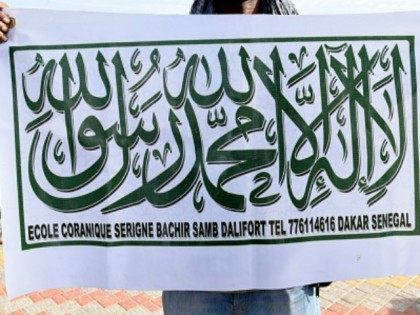 A demonstrator displays a banner featuring the Shahada (The Islamic creed stating a belief