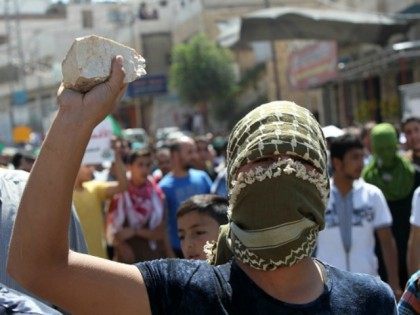 Palestinian protester holds a stone during clashes with Israeli security forces following