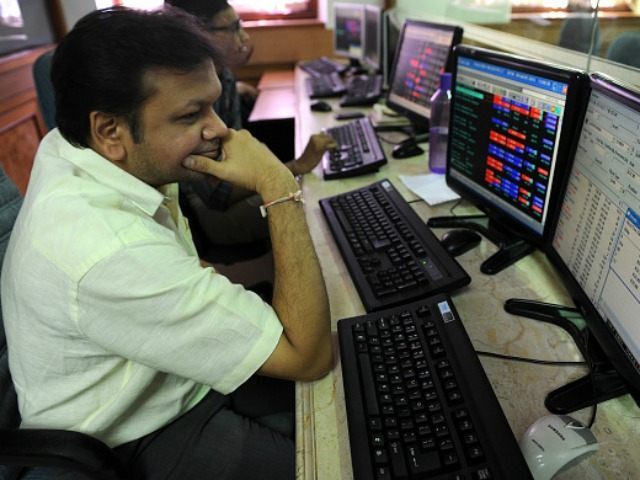 Indian stockbroker watches share prices on his trading screens at a brokerage house during