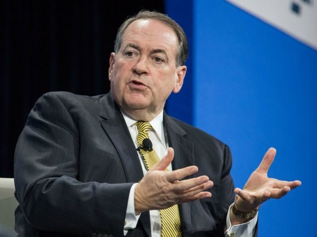 Republican presidential candidate Mike Huckabee speaks with moderators at an economic foru