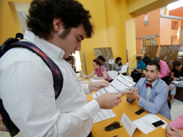 In this Tuesday, Oct. 6, 2015, photo, Alexander Haupt, left, 21, of Miami, looks over his job application as he speaks with Brooks Brothers Factory Store assistant store manager Daniel Lago, center, and visual merchandiser Barbie Pacheco, right, during a job fair at Dolphin Mall in Miami. The U.S. Labor …