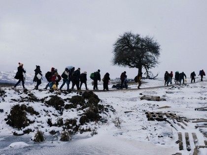 TOPSHOT - Migrants and refugees walk through snow covered fields, after crossing the Maced