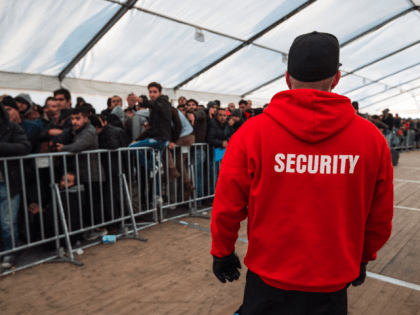 A member of the LAGeso security team watches over asylum-seekers queuing at the State Office of Health and Social Affairs (LAGeSo) registration centre in Berlin on December 10, 2015.