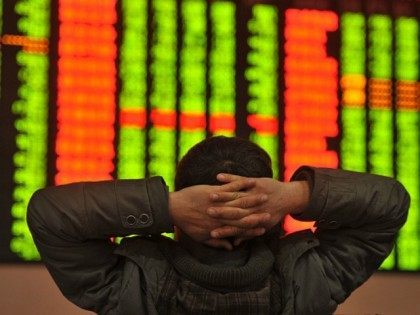 An investor sits in front of a screen showing stock market movements in a stock firm in Fu