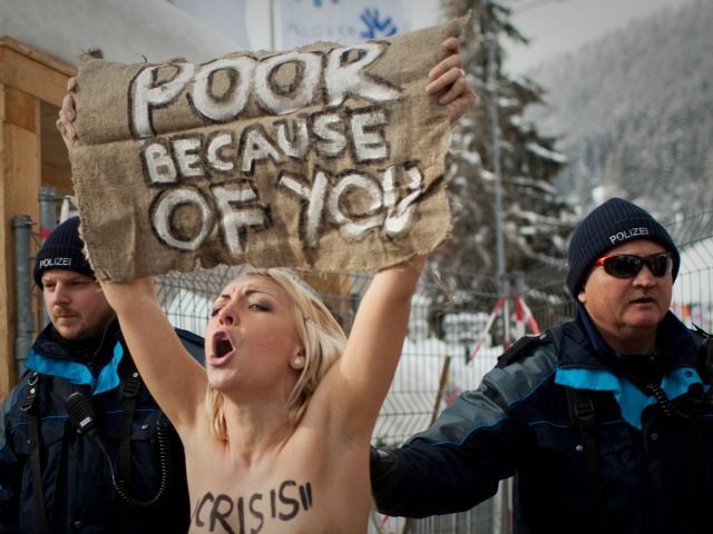 A topless Ukrainian protester is arrested by Swiss police after climbing up a fence at the entrance to the congress center where the World Economic Forum takes place in Davos, Switzerland Saturday, Jan. 28, 2012. The activists are from the group Femen, which has have become popular in Ukraine for staging small, half-naked protests against a range of issues including oppression of political opposition. (AP Photo/Anja Niedringhaus)