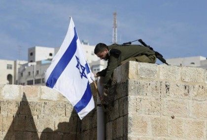 An Israeli soldier removes the Israeli flag from a house as Israeli troops forcibly remove