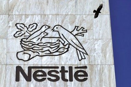 A crow flies above a sign of the world's biggest food company Nestle at their headqua