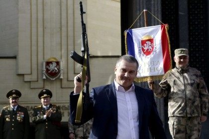 Russian acting leader of Crimea Sergei Aksyonov (C) holds a model of AK-47 automatic rifle