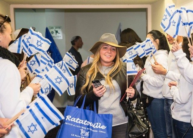 Jewish new immigrant from France, Alexandra Schneider, who is making Aliyah (Immigration to Israel) is welcomed by Israelis waving national flags upon her arrival at Ben Gurion International airport on December 8, 2015 in Lod, about 15 kms east of Tel Aviv, during the Jewish holiday of Hanukkah.