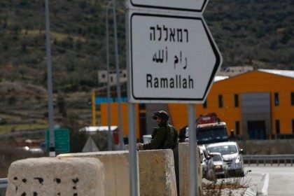 An Israeli soldier stands guard as he checks Palestinians' vehicles on their way out of the West Bank village of Ein Sinya, northern Ramallah on February 1, 2016.