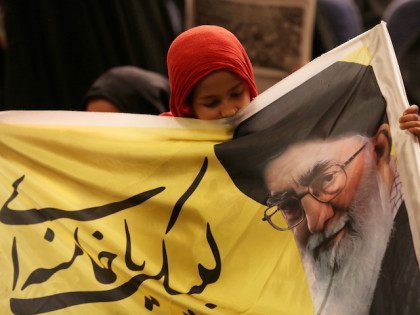 An Iranian girl holds a banner bearing a portrait of supreme leader Ayatollah Ali Khamenei during a campaign meeting of the head of the conservatives' grand coalition of principalists for the upcoming parliamentary elections, Gholam Ali Haddad Adel on February 21, 2016 at Baqiyatallah mosque in the capital Tehran. Voters …
