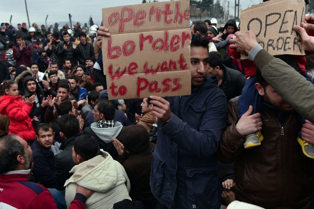 Syrian and Iraqi refugees trapped at the Greek-Macedonian border protest demanding the opening of the borders on February 28, 2016. More than 5,000 people were trapped at the Idomeni camp after four Balkan countries announced a daily cap on migrant arrivals. Slovenia and Croatia, both EU members, and Serbia and Macedonia said they would restrict the number of daily arrivals to 580 per day. / AFP / LOUISA GOULIAMAKI (Photo credit should read LOUISA GOULIAMAKI/AFP/Getty Images)