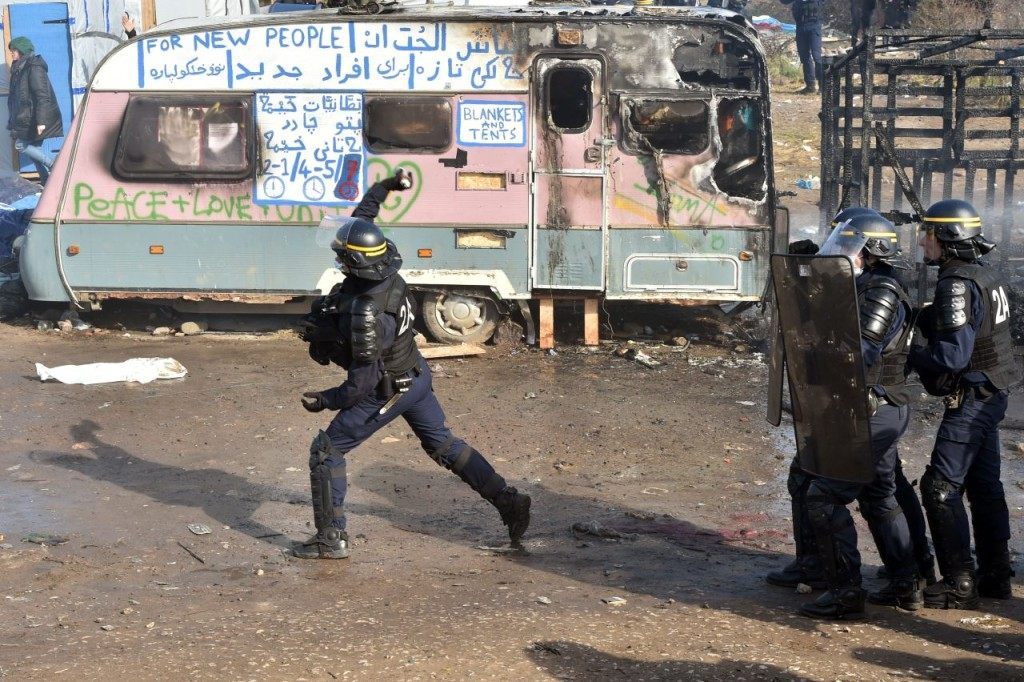 An anti-riot policeman throws a tear gas grenade on February 29, 2016, during the dismantling of half of the "Jungle" migrant camp in the French northern port city of Calais. Two bulldozers and around 20 workers began destroying makeshift shacks, with 30 police cars and two anti-riot vans stationed nearby. AFP PHOTO / PHILIPPE HUGUEN / AFP / PHILIPPE HUGUEN (Photo credit should read PHILIPPE HUGUEN/AFP/Getty Images)