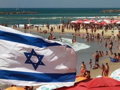 An Israeli flag flutters above umbrellas on the beach in the Mediterranean city of Tel Aviv on August 11, 2015. Decision to dedicate a day of beach parties in the French capital to Israel's most famous beach city sparks condemnation from pro-Palestinian group saying it sends 'very bad message' of …