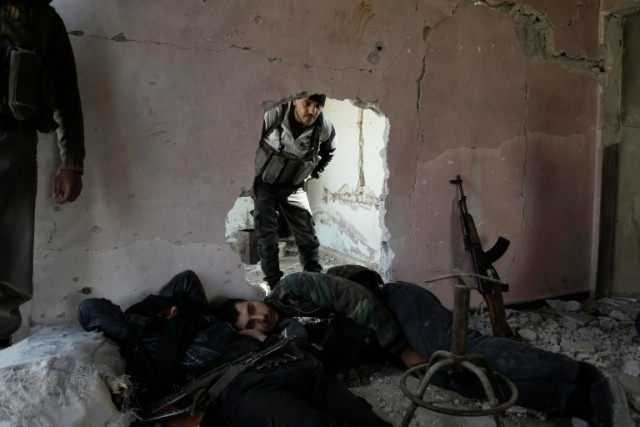 Syrian rebel fighters from the Failaq al-Rahman brigade rest during a lull in fighting aga