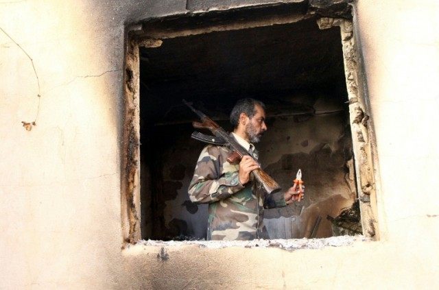 A fighter loyal to Libya's internationally recognised government checks a damaged house in