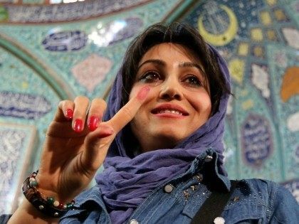 An Iranian woman displays her ink-stained finger after casting her ballot for both parliamentary elections and the Assembly of Experts at a polling station in Tehran, on February 26, 2016