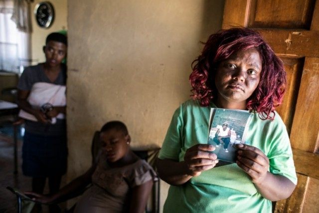 Jamina Tangasha, one of the late Seun Tangasha's sisters, holds up a photo of him in Parys