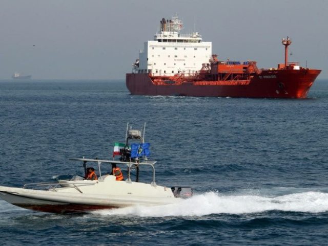 An Iranian Revolutionary Guard speedboat cruises past an oil tanker off the port of Bandar