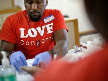 Reggie Batiste, left, program manager with AIDS Healthcare Foundation, administers a free HIV test as part of National HIV Testing Day, Thursday, June 27, 2013, in Atlanta. Health officials say more than 1.1 million people in the U.S. are living with HIV, but 20 percent of them don't know it. …