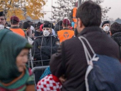 Austrian police officers stand guard as migrants and refugees wait …