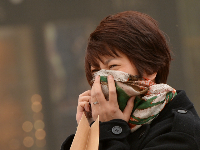 A Chinese woman tries to protect herself as Beijing is hit by a sandstorm Getty
