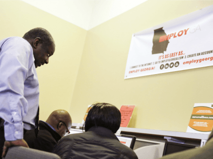 Georgia Department of Labor services specialist Eric Frasier, left, helps a woman with a job search at an unemployment office, Thursday, March 3, 2016, in Atlanta.