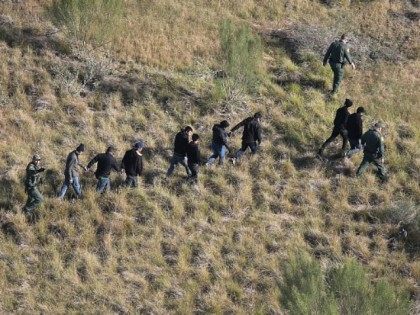 Border Patrol agents lead undocumented immigrants out the brush after capturing them near the U.S.-Mexico border on December 10, 2015 at La Grulla, Texas. Border security remains a key issue in the U.S. Presidential campaign. (Photo by