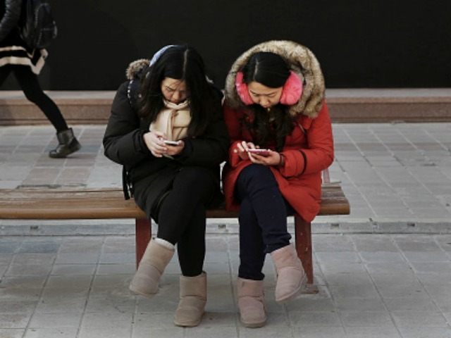 Chinese women check their mobile phones at a market on January 19, 2016 in Beijing, China.