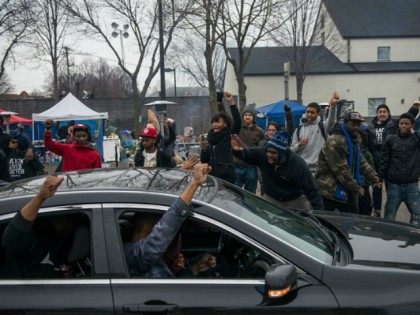 Members of the funeral procession for Jamar Clark join protestors, raising their fists out
