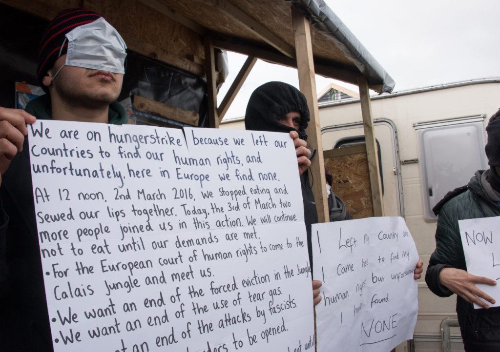 Iranian migrants who sew their lips to protest against the dismantling of the southern half of the so-called "Jungle" migrant camp, stage a protest in the French northern port city of Calais, on March 3, 2016. Demolition workers razed makeshift shelters at the so-called Jungle migrant camp on the outskirts of Calais for a fourth day running on March 3, under the close watch of dozens of police officers equipped with water cannon. / AFP / DENIS CHARLET (Photo credit should read DENIS CHARLET/AFP/Getty Images)