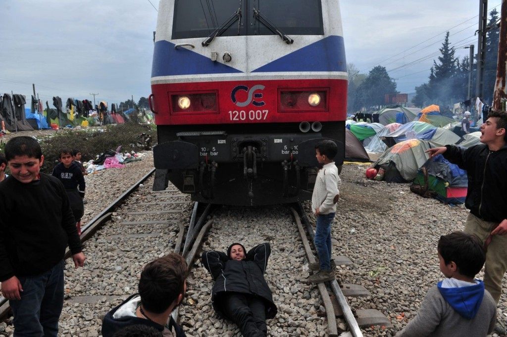 A man lies on railway tracks as he demonstrates with other people at a makeshift camp near the Greek village of Idomeni by the Greek-Macedonian border where thousands of refugees and migrants are trapped by the Balkan border blockade, on March 12, 2016. Greece aims to deal swiftly with the migrant overflow at the Idomeni refugee camp on the Greek-Macedonian border where some 12,000 people are camping in miserable conditions waiting to cross. Conditions in the camp have worsened since four Balkan countries shut their borders on March 8 and 9, closing off the main route to wealthy northern Europe trodden by hundreds of thousands of migrants in the last two years. / AFP / SAKIS MITROLIDIS (Photo credit should read SAKIS MITROLIDIS/AFP/Getty Images)