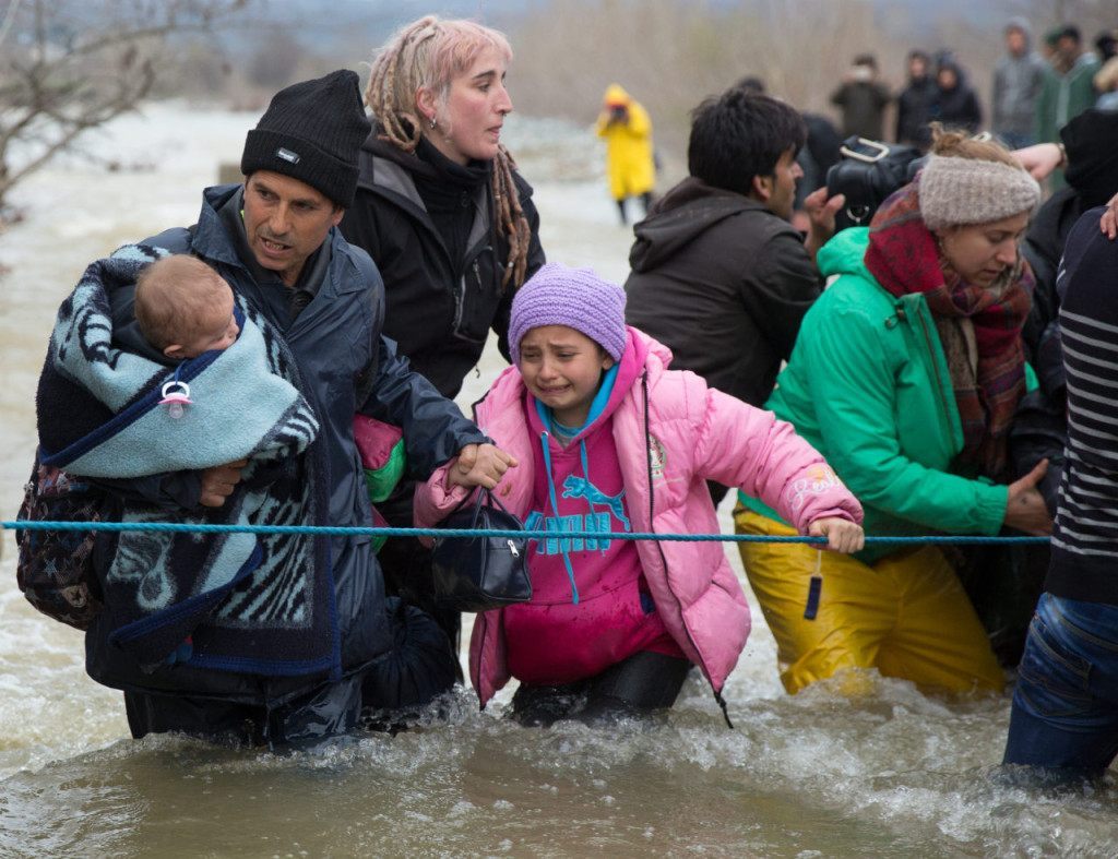 IDOMENI, GREECE - MARCH 14: Migrants cross a river after leaving the Idomeni refugee camp on March 14, 2016 in Idomeni, Greece. The decision by Macedonia to close its border to migrants on Wednesday has left thousands of people stranded at the Greek transit camp. The closure, following the lead taken by neighbouring countries, has effectively sealed the so-called western Balkan route, the main migration route that has been used by hundreds of thousands of migrants to reach countries in western Europe such as Germany. Humanitarian workers have described the conditions at the camp as desperate, which has been made much worse by recent bouts of heavy rain. (Photo by Matt Cardy/Getty Images)
