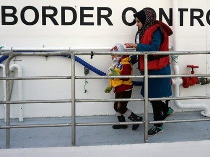 A woman and her child disembarks from a Norwegian Frontex vessel at the port of Mytilene