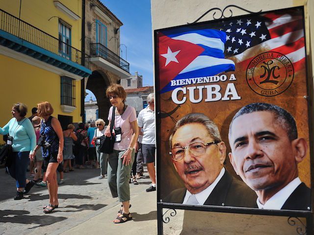 Tourists walk next to a poster of Cuban President Raul Castro and US president Barack Obam
