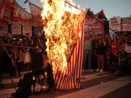 Members of leftist organizations burn a flag representing the US during a protest against