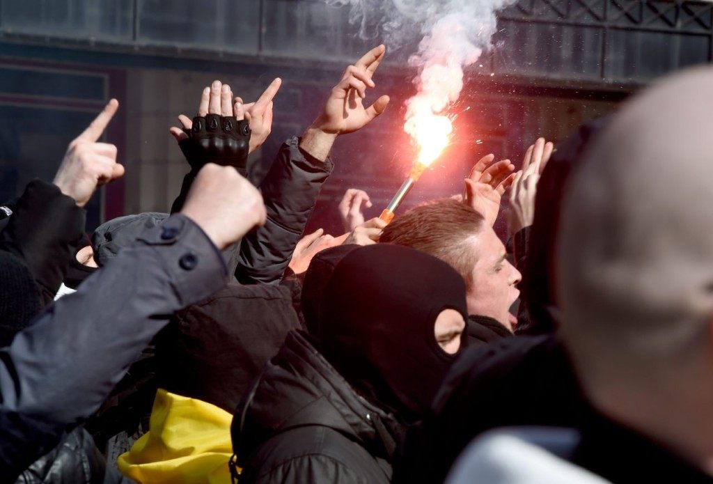 Far-right football hooligans chant slogans as they arrive oputside teh stock exchaneg in Brussels on March 27, 2016 an area which has become an unofficial shrine to victims of the March 22, terror attacks claimed by the Islamic State (IS) group in which 31 people were killed and over 300 injured. Police used a water cannon to disperse far-right football hooligans outside the stock exchange in Brussels, where people have laid floral tributes to the victims of the March 22, terror attacks on the city. / AFP / PATRIK STOLLARZ (Photo credit should read PATRIK STOLLARZ/AFP/Getty Images)