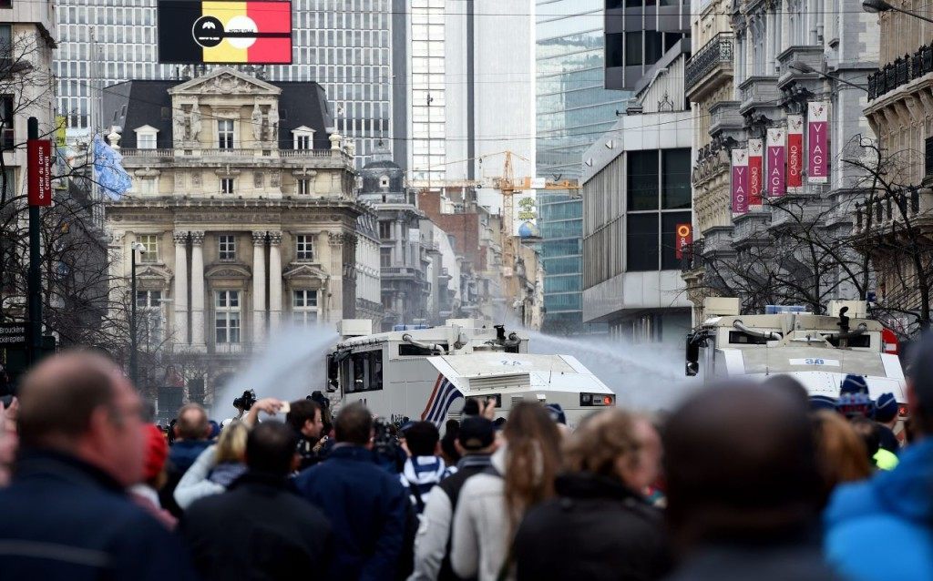 Police use a water cannon to disperse far-right football hooligans outside the stock exchange in Brussels on March 27, 2016 an area which has become an unofficial shrine to victims of the March 22, terror attacks claimed by the Islamic State (IS) group in which 31 people were killed and over 300 injured. Police used a water cannon to disperse far-right football hooligans outside the stock exchange in Brussels, where people have laid floral tributes to the victims of the March 22, terror attacks on the city. / AFP / PATRIK STOLLARZ (Photo credit should read PATRIK STOLLARZ/AFP/Getty Images)