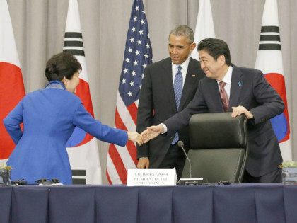 U.S. President Barack Obama (C) watches Japanese Prime Minister Shinzo Abe (R) shake hands