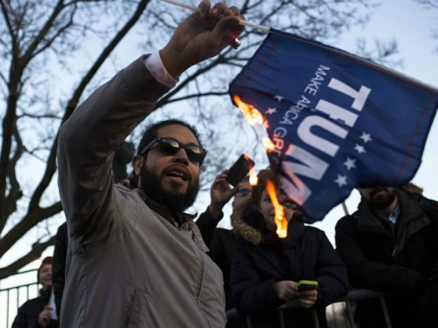 protester burns a flag outside of the University of Illinois at Chicago Pavilion where Republican presidential candidate Donald Trump is due to speak at a campaign rally March 11, 2016 in Chicago, Illinois. The rally was later cancelled for safety concerns.