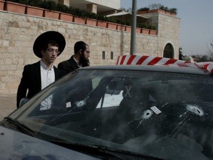 Religious Jews check a vehicle with its windshield riddled with bullet holes at the scene