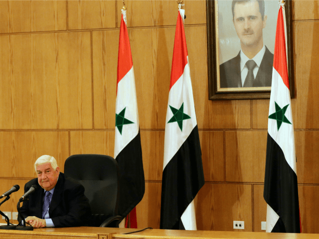 Syrian Foreign Minister Walid Muallem speaks during a press conference in front of a portr