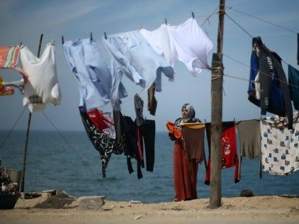 A Palestinian woman hangs her laundry next to her house at al-Shatee refugee camp in Gaza
