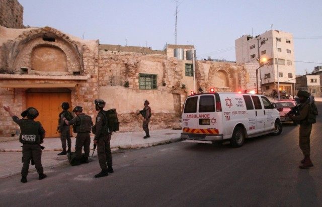 Israeli security forces gather at the site of a stabbing attack in the West Bank town of H