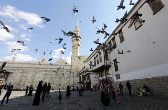 Syrians watch pigeons flying outside the Umayyad Mosque in the Syrian capital, Damascus, on November 10, 2015