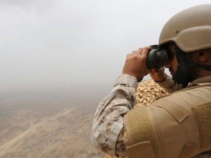A Saudi soldier looks through binoculars from a position in the al-Dokhan mountains, on th